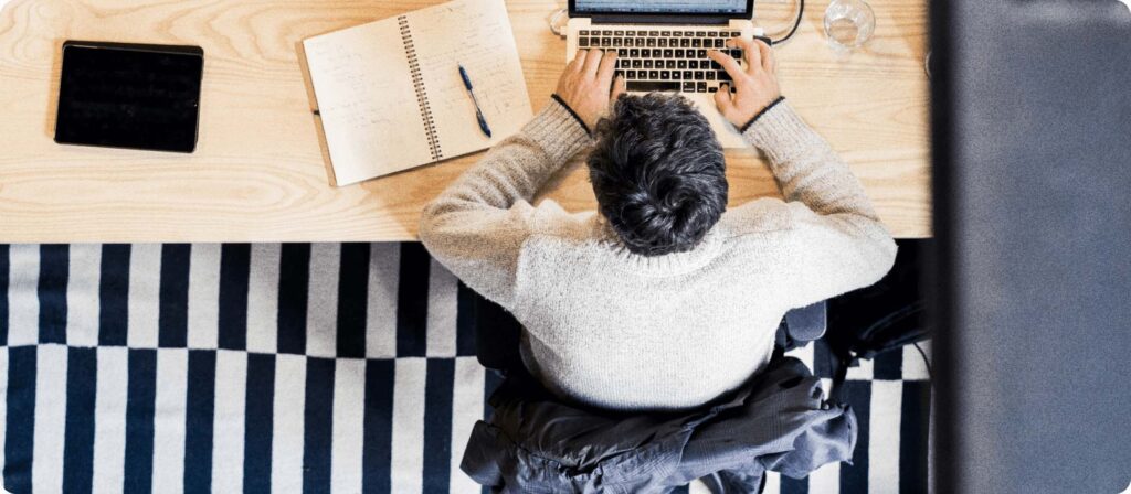 Ein Mann am Schreibtisch mit einem Laptop und Notizblock