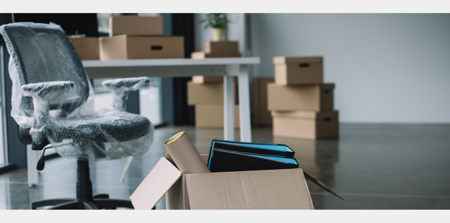 Einrichtung eines neuen Arbeitsplatzes - Schreibtisch, Bürostuhl, Ordner und Büromaterial in Kartons
