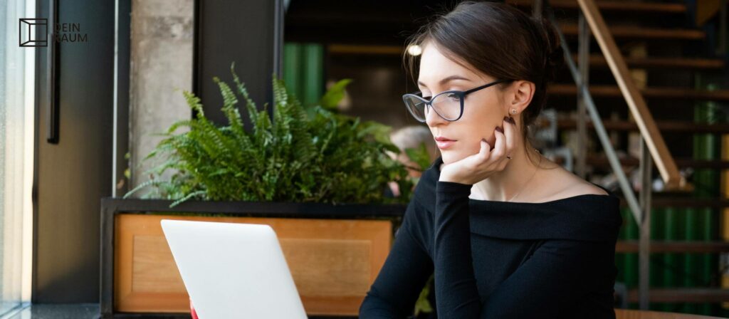 Frau mit Brille an ihrem Arbeitsplatz am Laptop