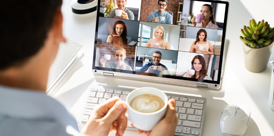 ine Person hält eine Tasse Kaffee und nimmt an einem virtuellen Meeting mit mehreren Personen teil, die ebenfalls ihre Tassen in einer Videochat-Ansicht halten. Es verdeutlicht, wie moderne Arbeitsumgebungen Flexibilität und soziale Interaktionen im Homeoffice kombinieren.